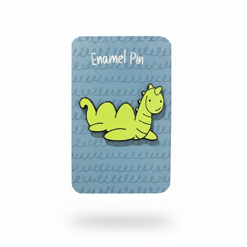 Nessie enamel pin on its illustrated backing card, held in a hand
