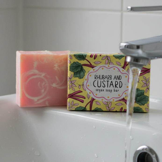 Rhubarb and custard soap bar and box on bathroom sink with running tap