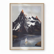A framed art print depicting a snowy mountain range over a calm lake with a small sailboat, hung on a light beige wall with soft shadow overlays.