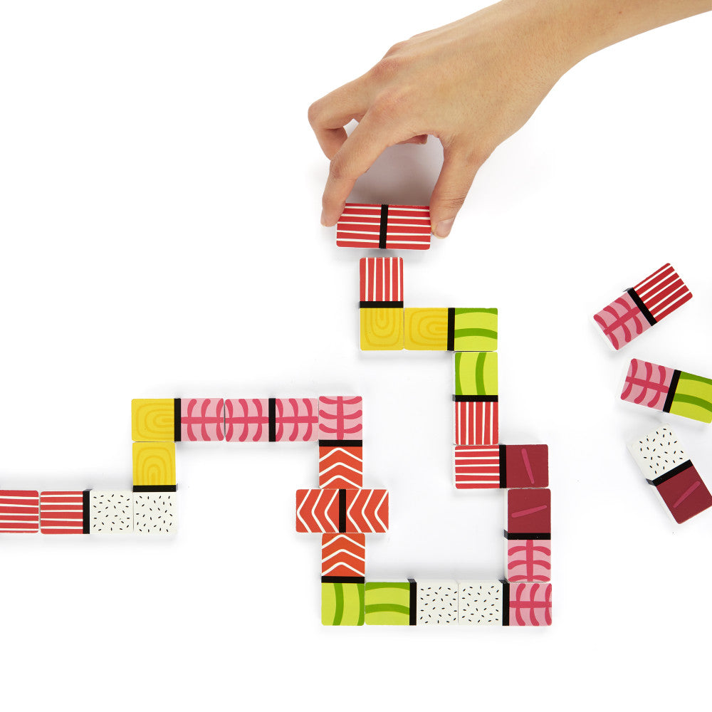 Hand placing sushi domino pieces in chain pattern