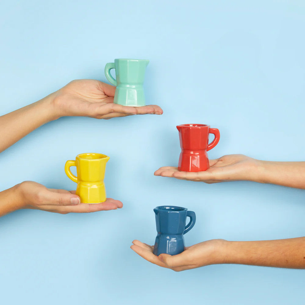 Four hands holding multicolour espresso cups against blue background