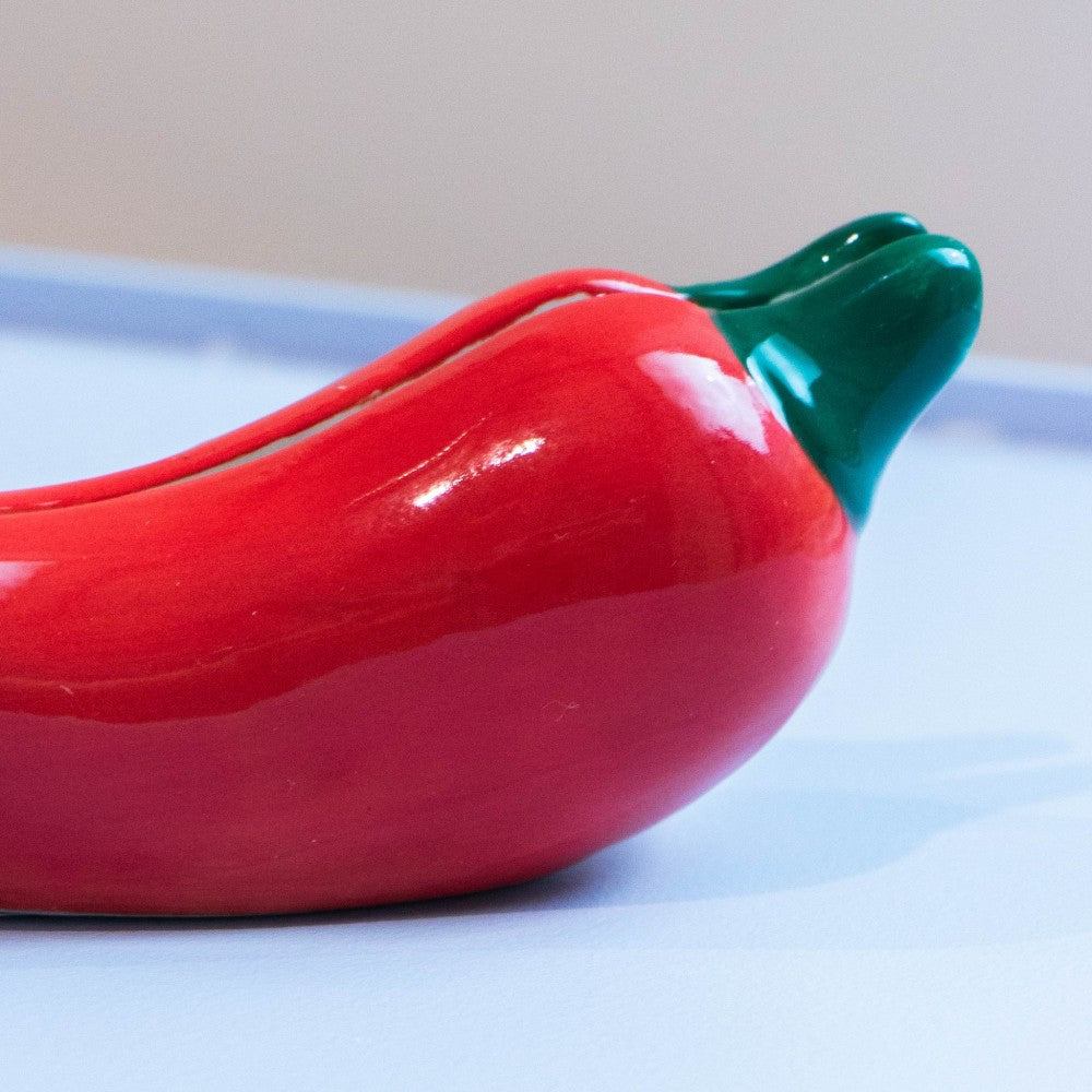 Hand placing photo into red pepper holder on wooden surface
