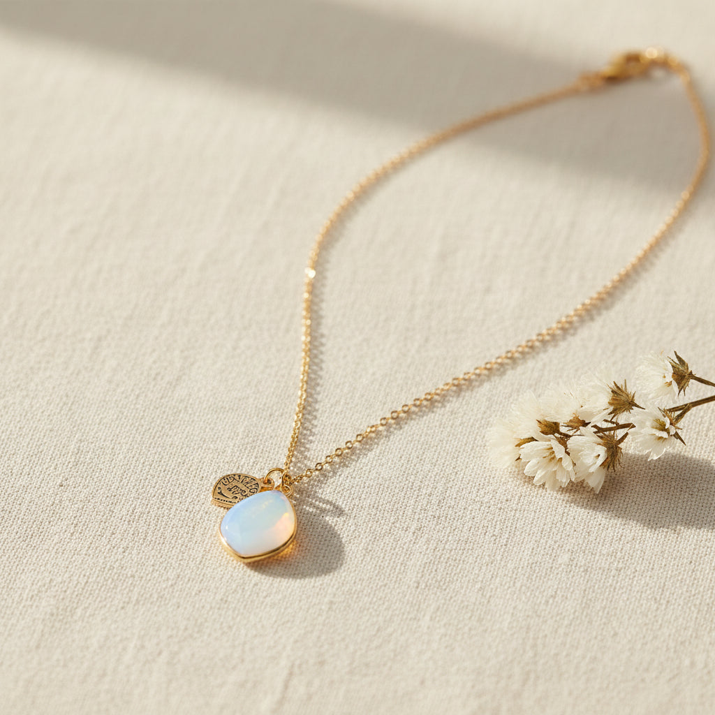 Full-length view of gold Opalite Manifestation Necklace with teardrop opalite pendant and celestial charm against white background.