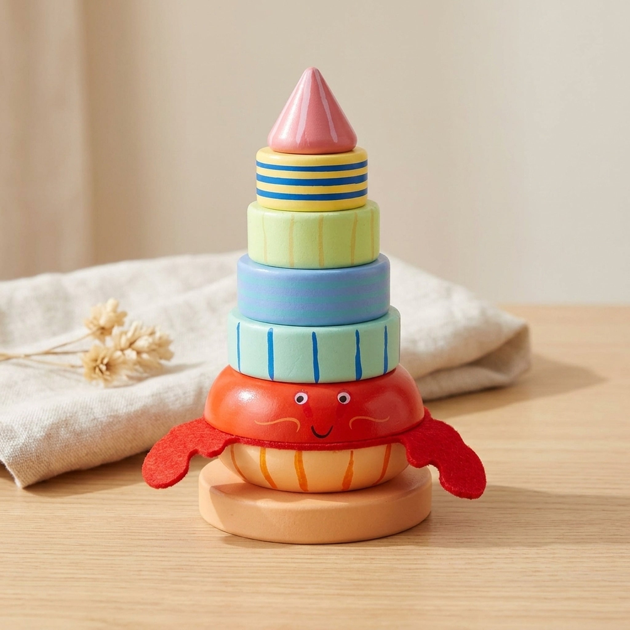 Hermit crab wooden stacking ring standing on a warm wood table with soft linen behind
