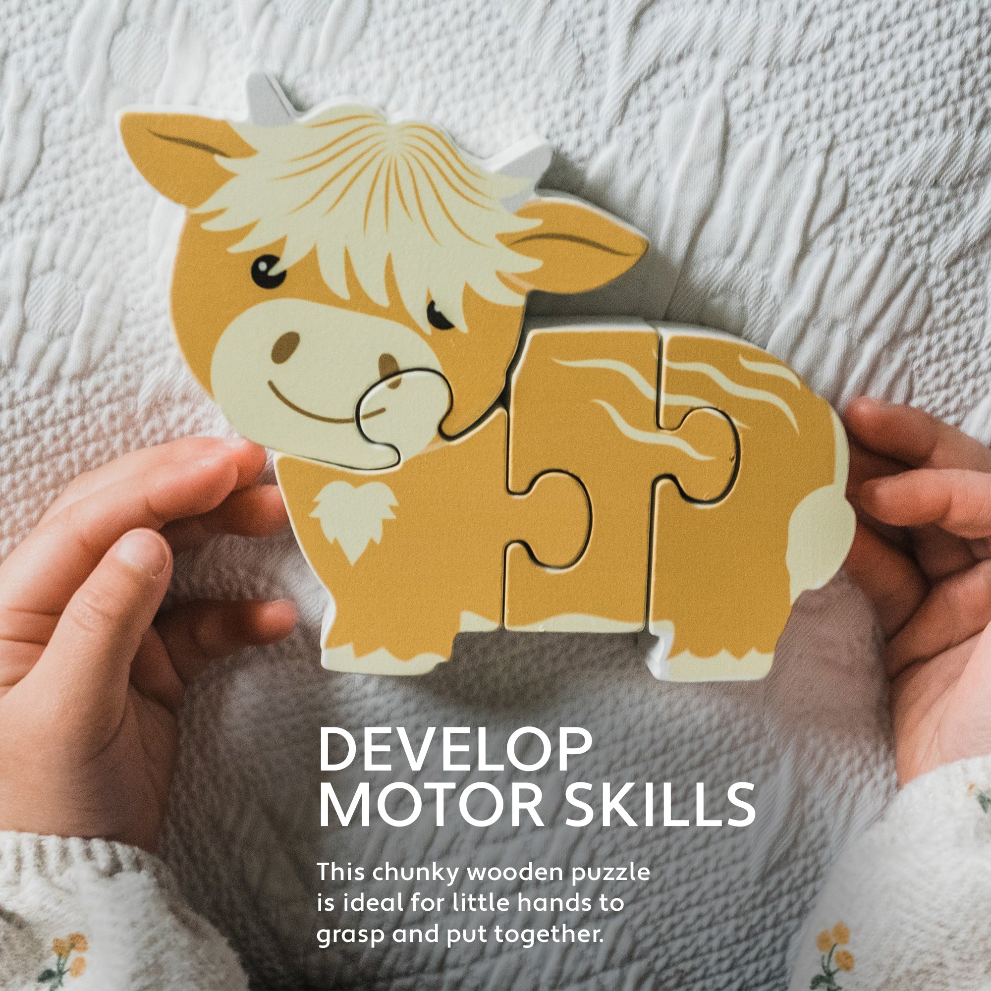 Hands holding the Highland cow wooden puzzle above a cream knitted blanket