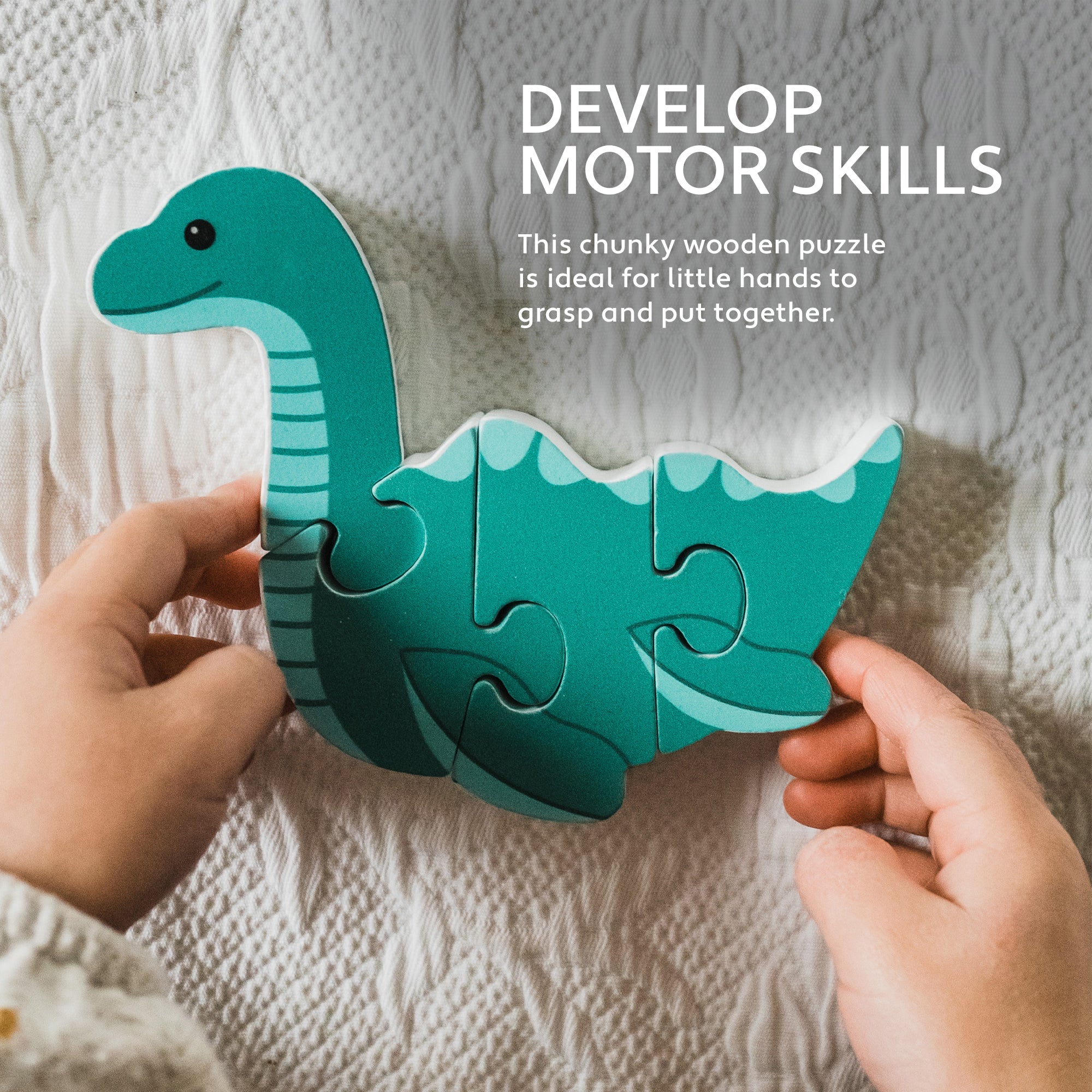 Hands fitting the Nessie wooden puzzle together on a pale grey blanket