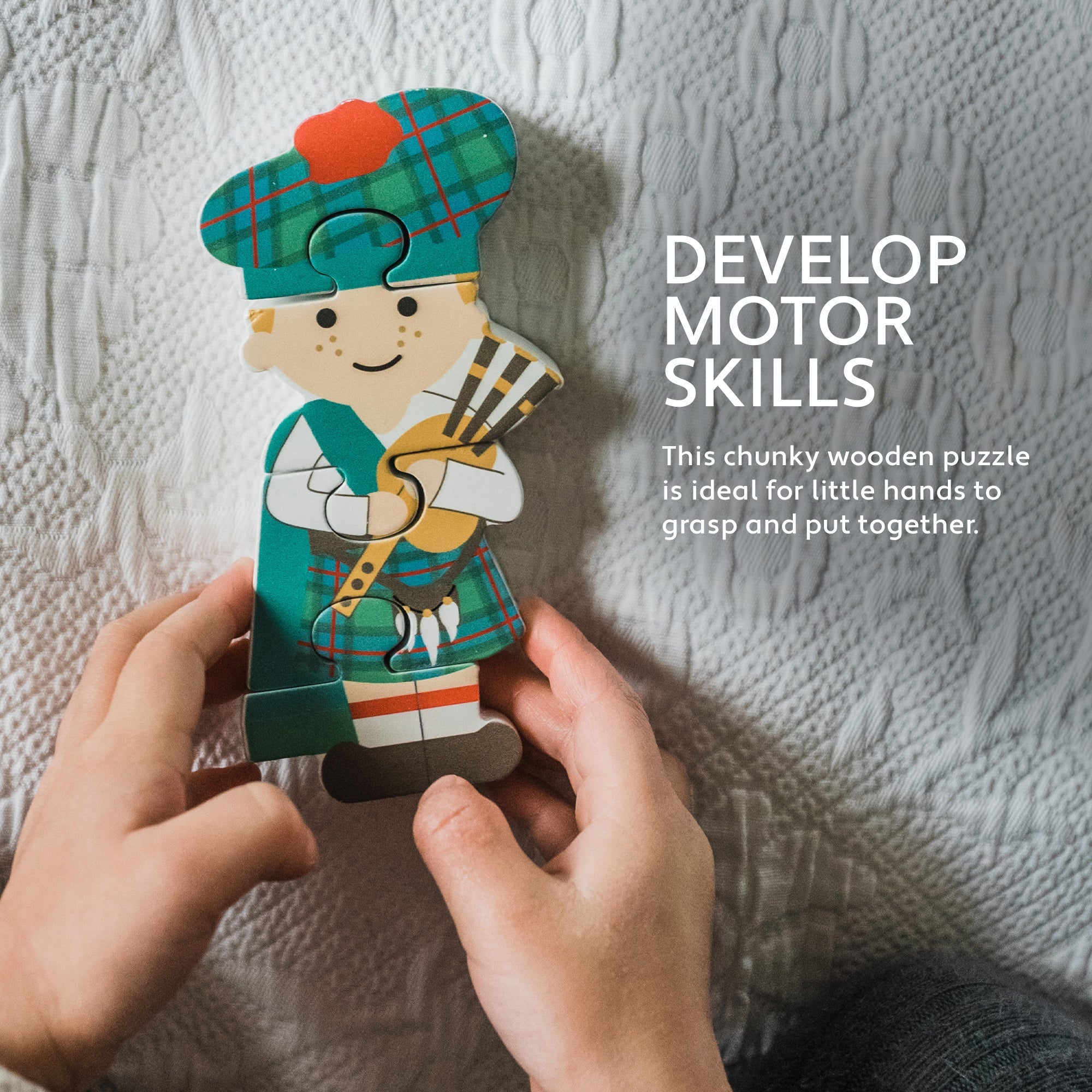 Hands fitting the Scottish piper wooden puzzle together on a pale blanket