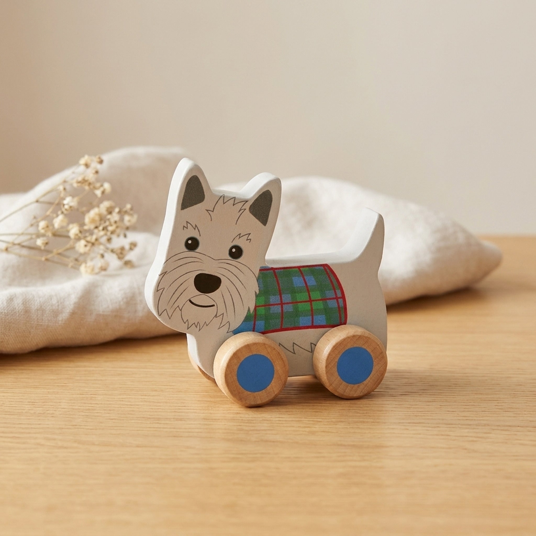 Scottie dog wooden push toy on a warm oak table with cream linen and dried flowers