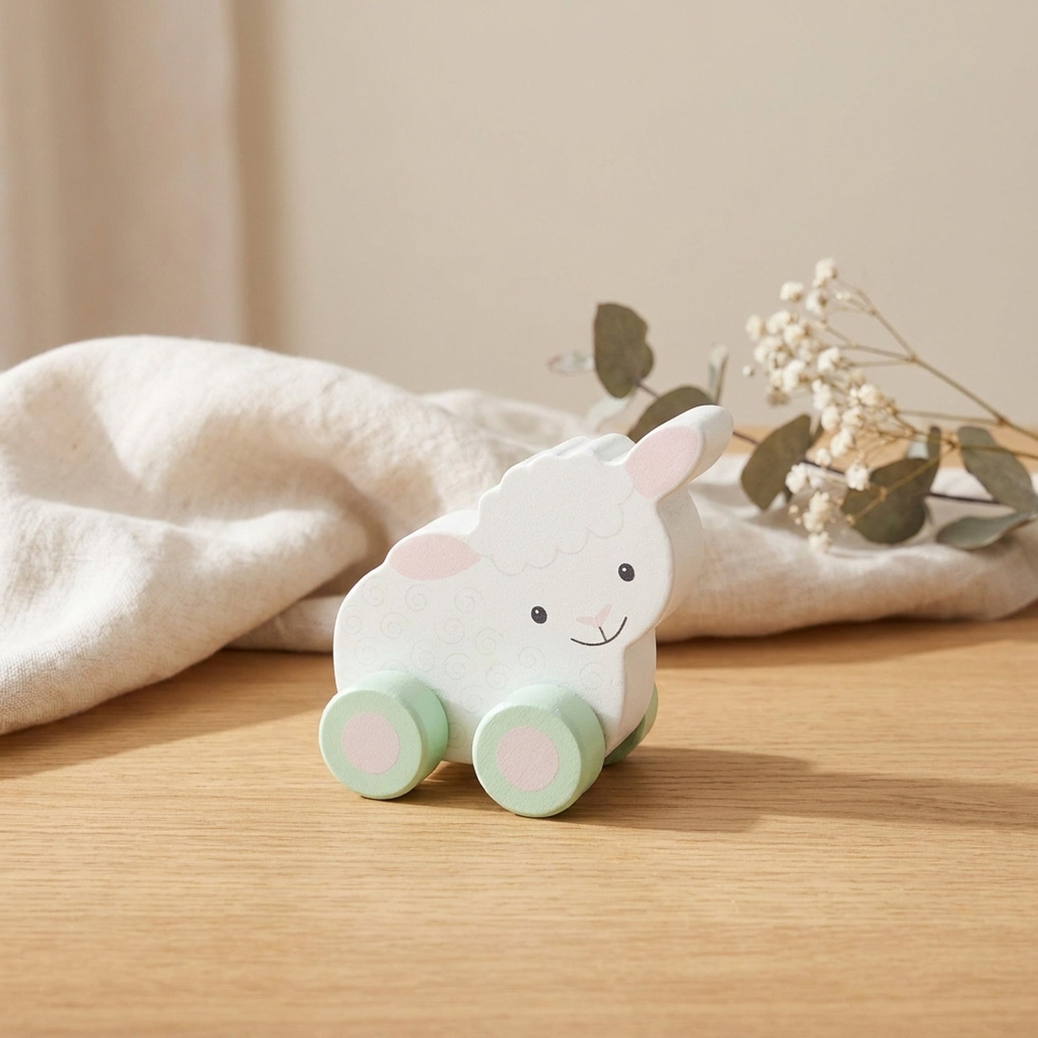 Sheep wooden push toy on a warm oak table with cream linen and dried flowers