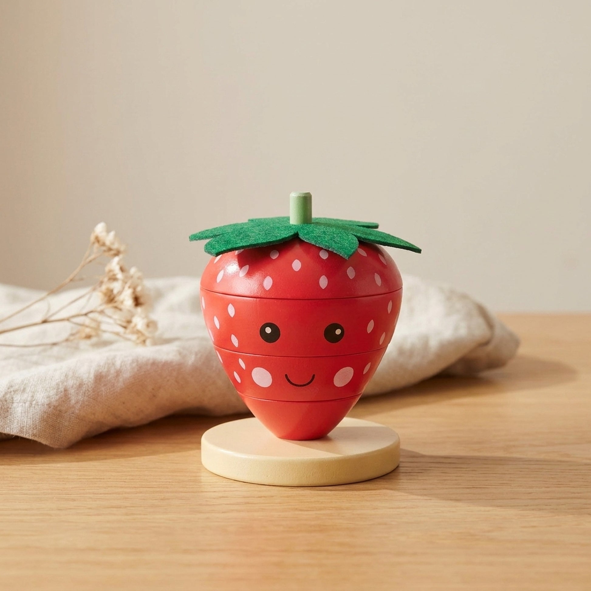 Strawberry wooden stacking ring standing on a warm wood table with soft linen behind