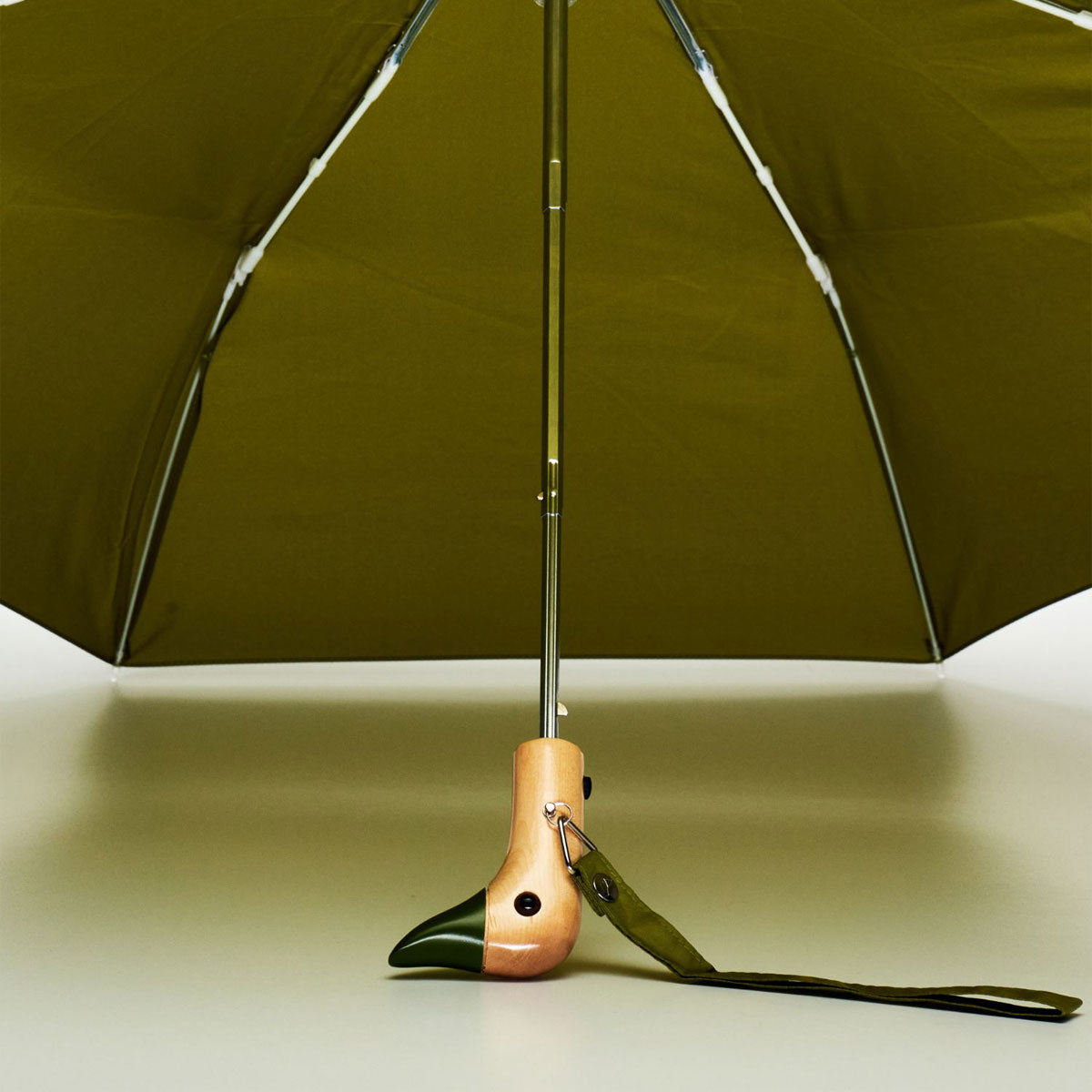 Olive duck umbrella open from underneath showing ribs and wooden handle