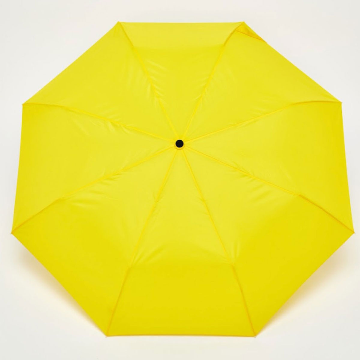 Top-down view of open yellow duck umbrella canopy on light background
