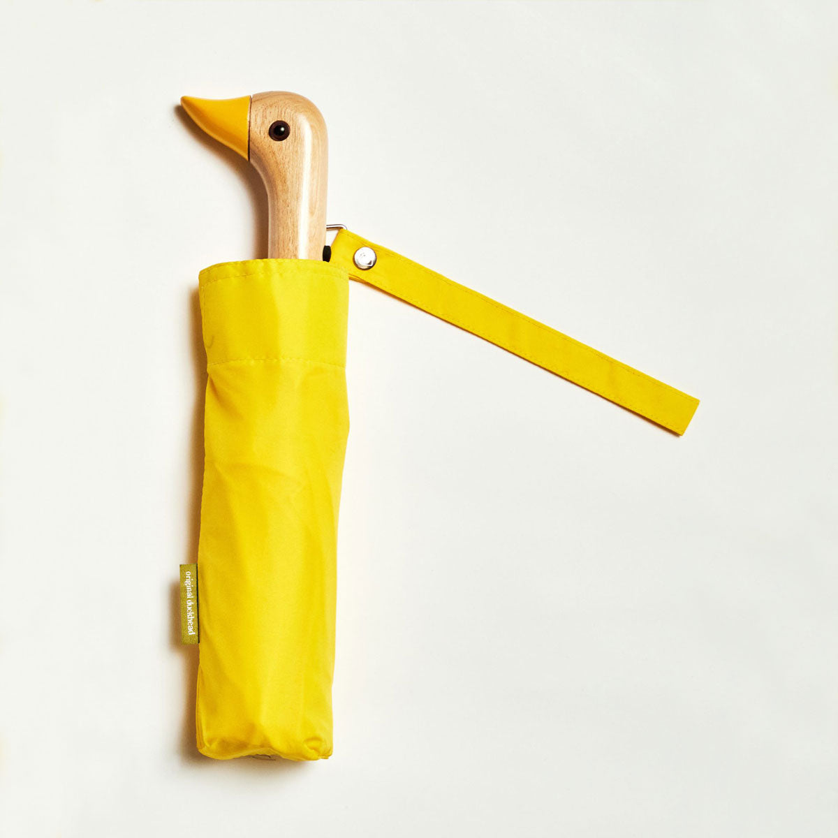 Closed yellow duck umbrella flat lay showing wooden duck head handle