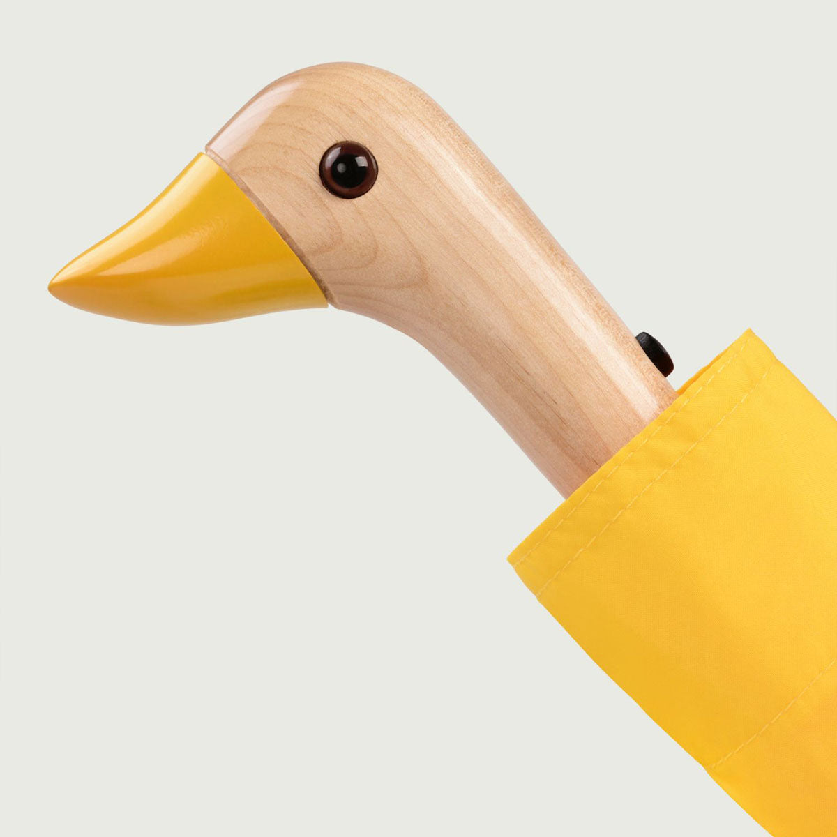 Close-up of wooden duck head handle with yellow beak on white background