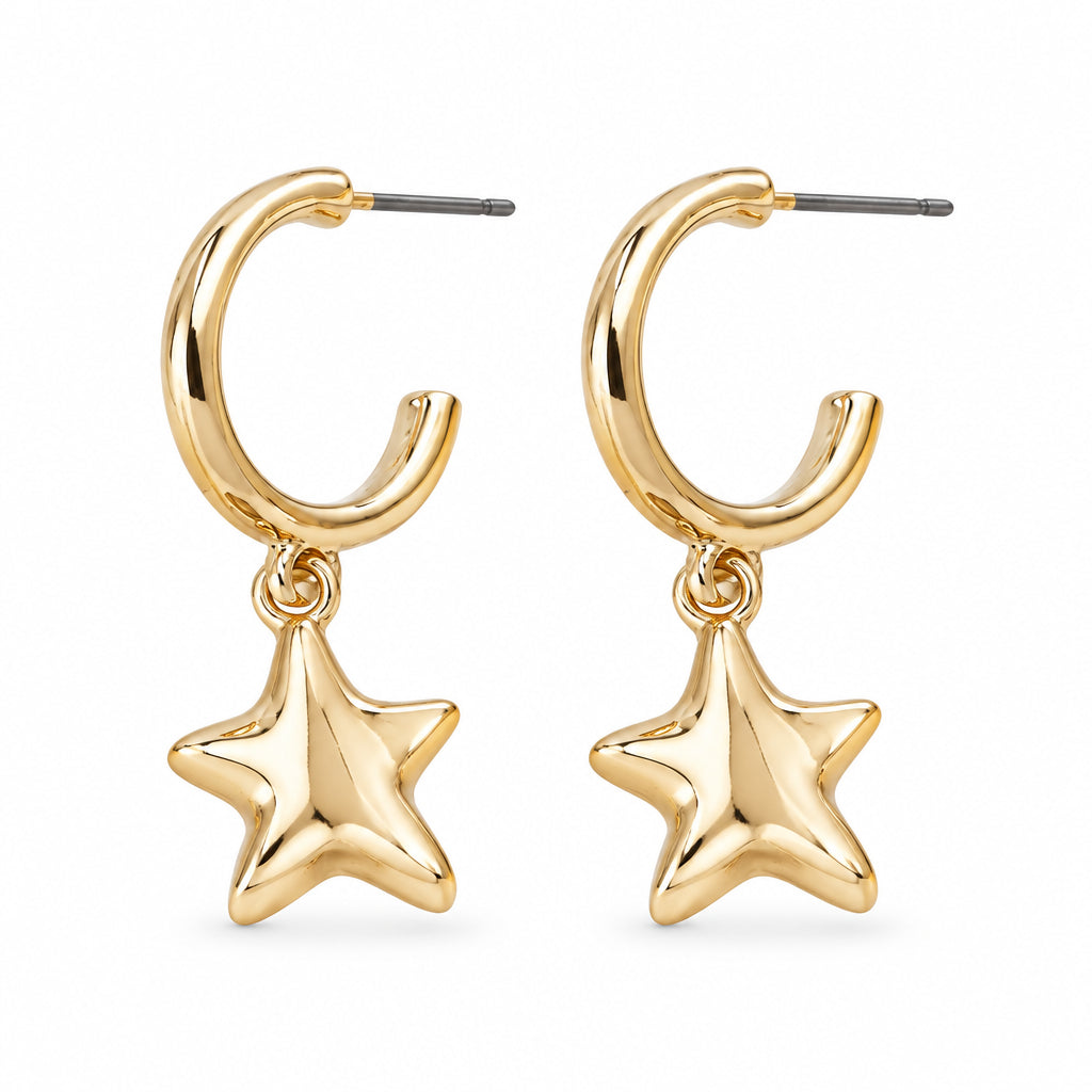 Gold C hoop earrings with wavy star charms beside a white dish on cream