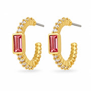 Gold hoop stud earrings with pink and clear crystals on a cream surface