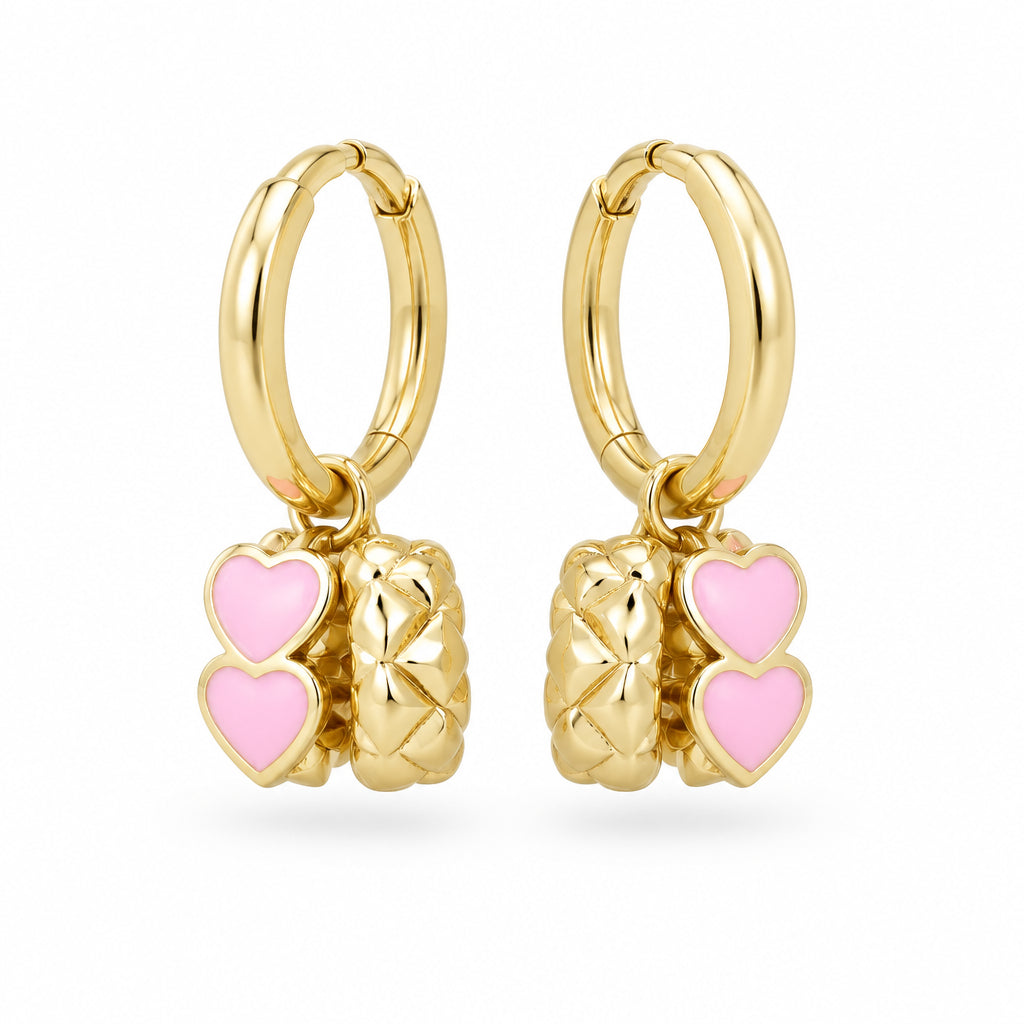 Gold hoop earrings with pink enamel and embossed heart rings on a cream surface