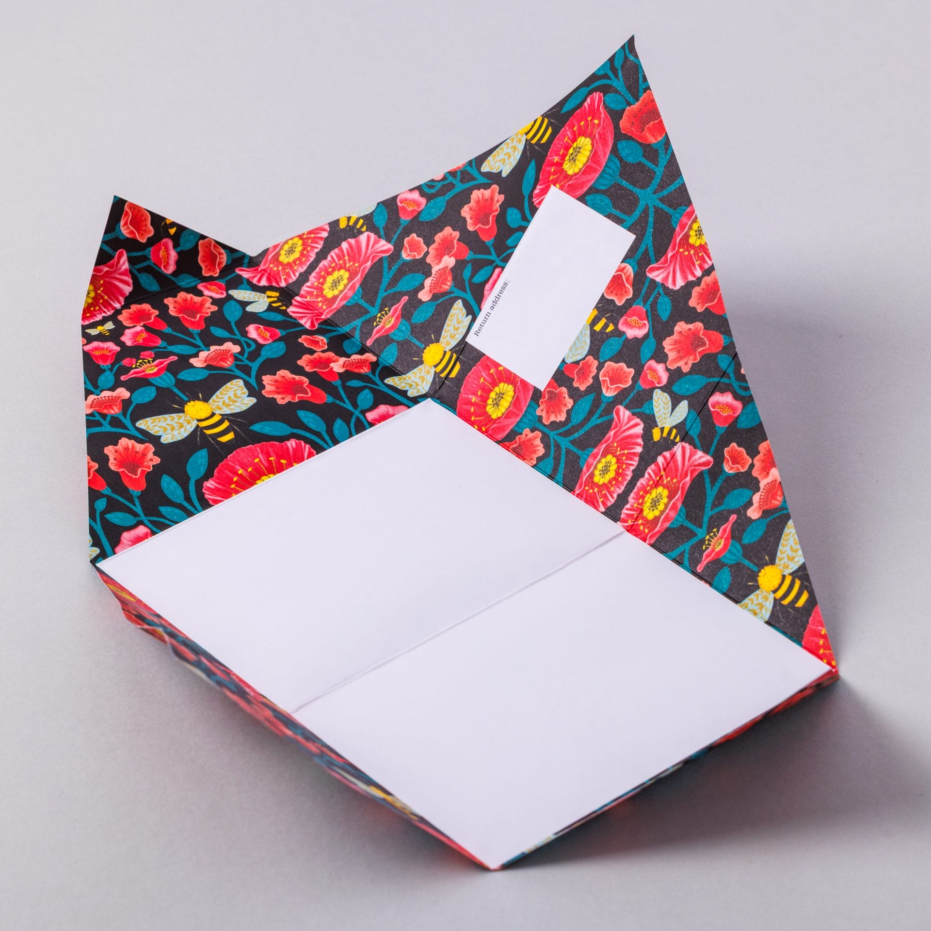 Unfolded Bright and Beautiful Pigeon showing colourful floral interior on grey background