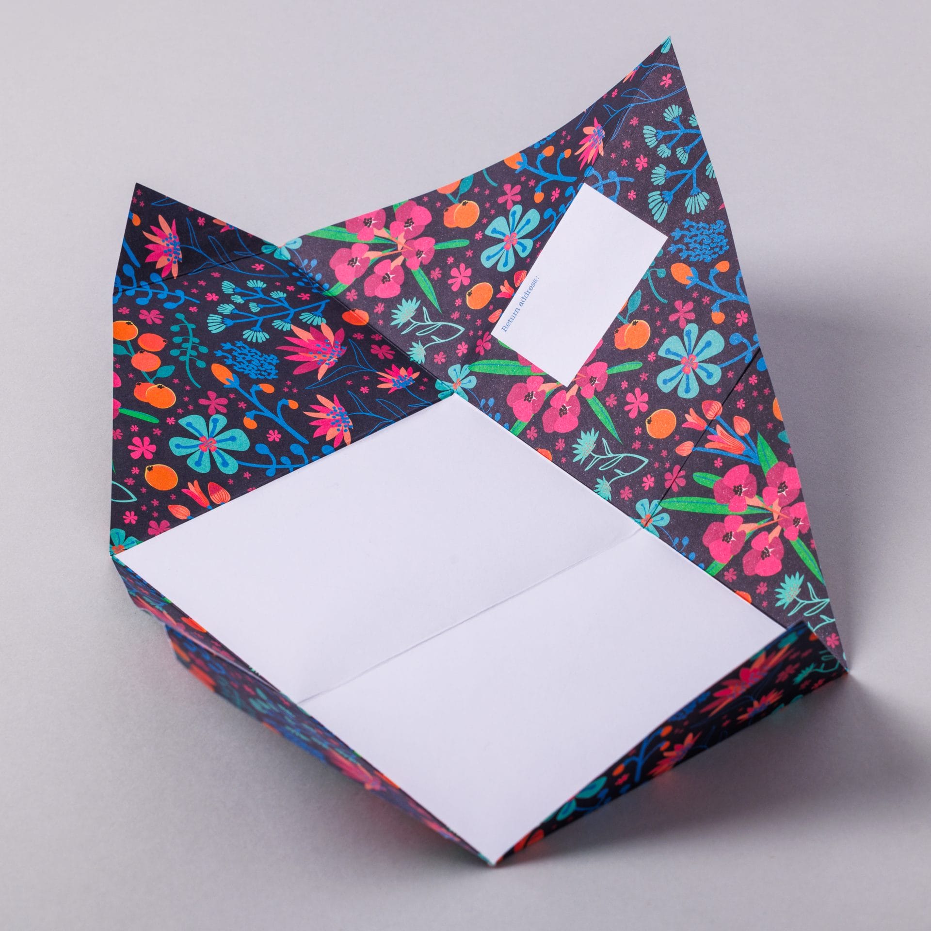 Unfolded Midnight Garden Pigeon showing dark floral interior on grey background