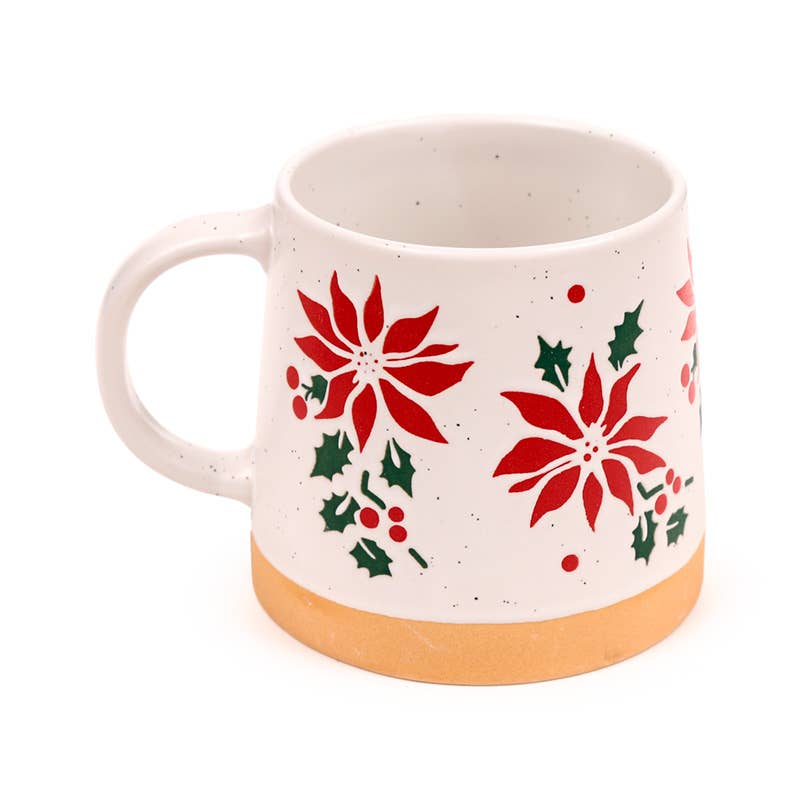 Poinsettia Tapered Stoneware Mug on a festive table beside Christmas decorations and cookies, filled with a warm drink.