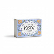 A boxed soap bar labeled 'a very tiny PORRIDGE soap bar' with a light blue illustrated front, photographed on a white surface against a soft gray background.