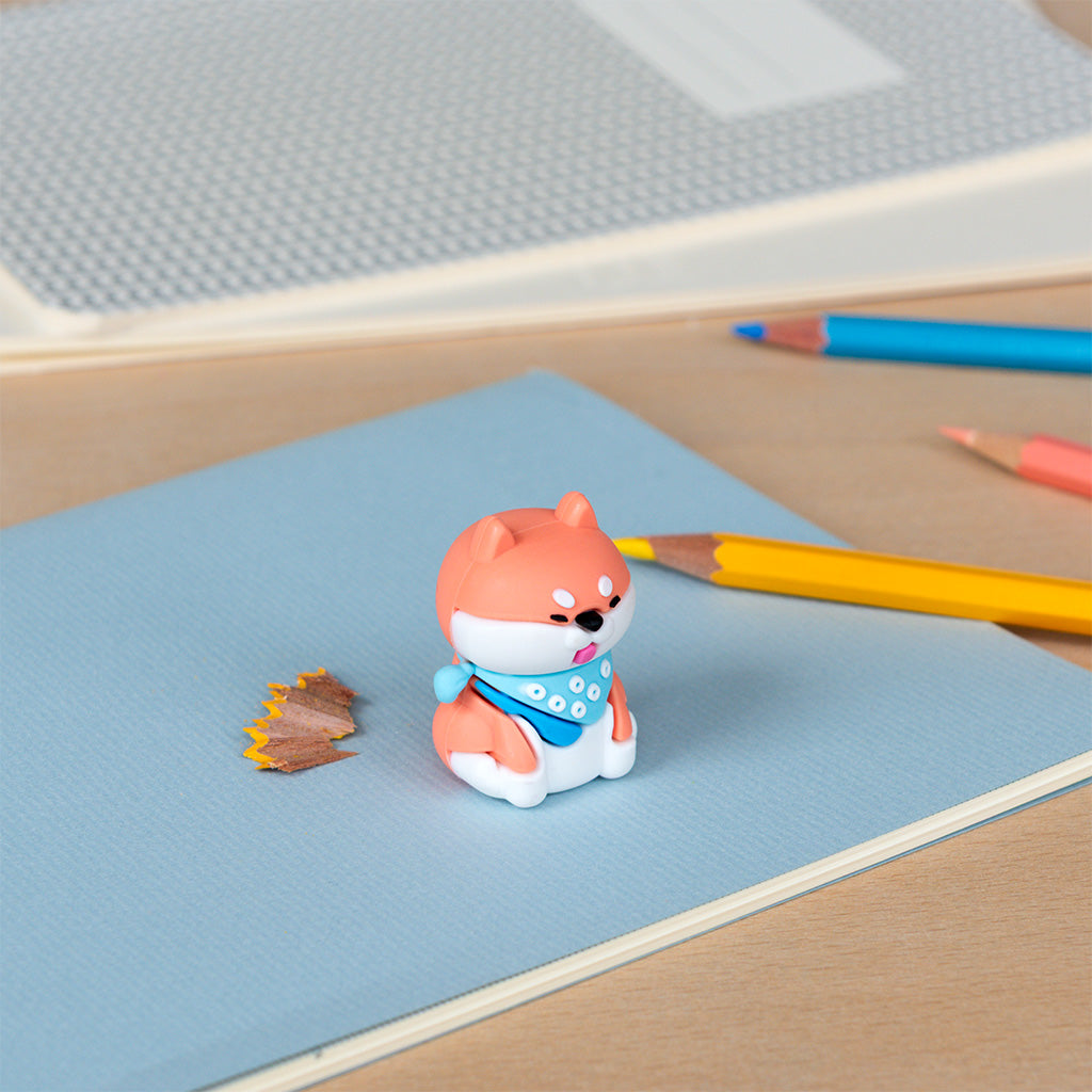 Dog pencil sharpener on a desk beside coloured pencils