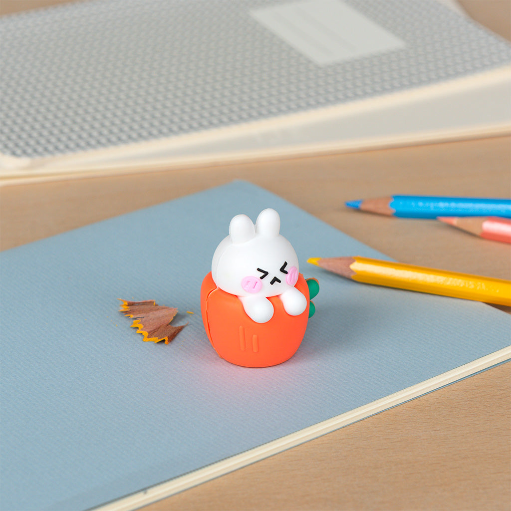 White rabbit pencil sharpener on a desk beside coloured pencils