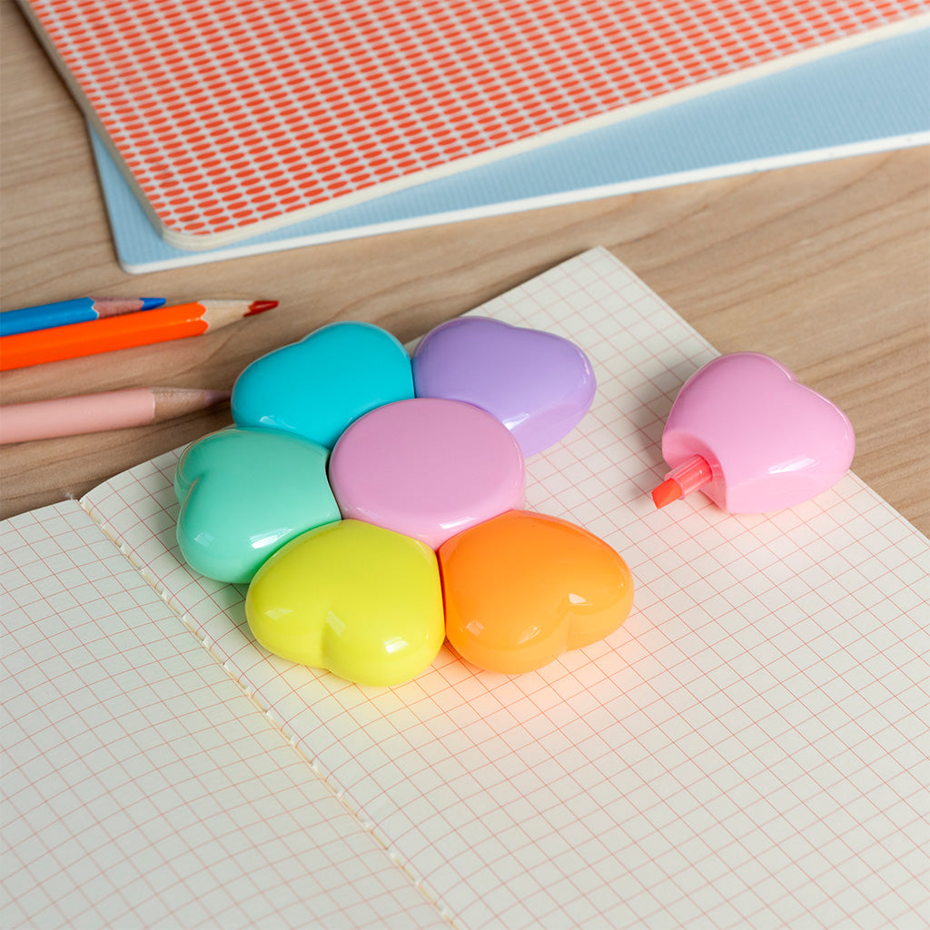 Flower shaped highlighters scattered on a desk beside a notebook