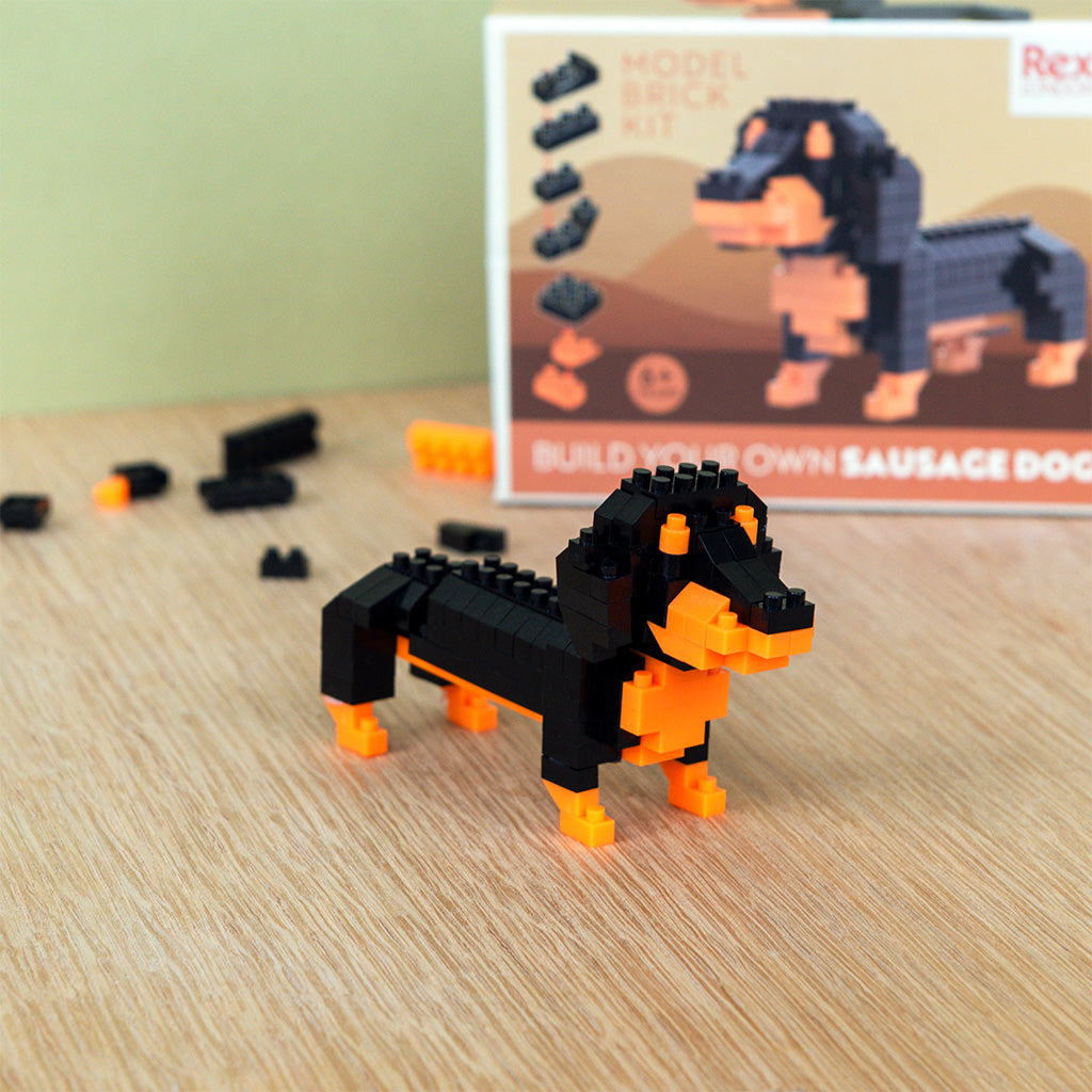 Part built micro brick dachshund on a wooden desk with loose bricks around it