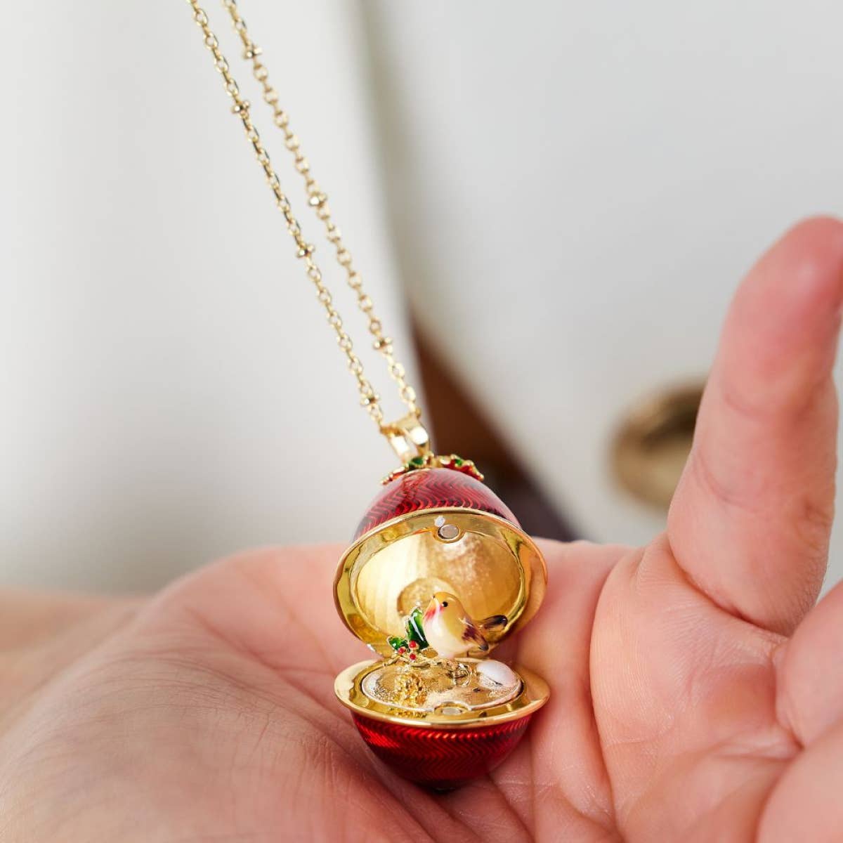 Bill Skinner Robin Egg Locket pendant open on gold chain showing detailed robin and holly scene inside red enamel egg.