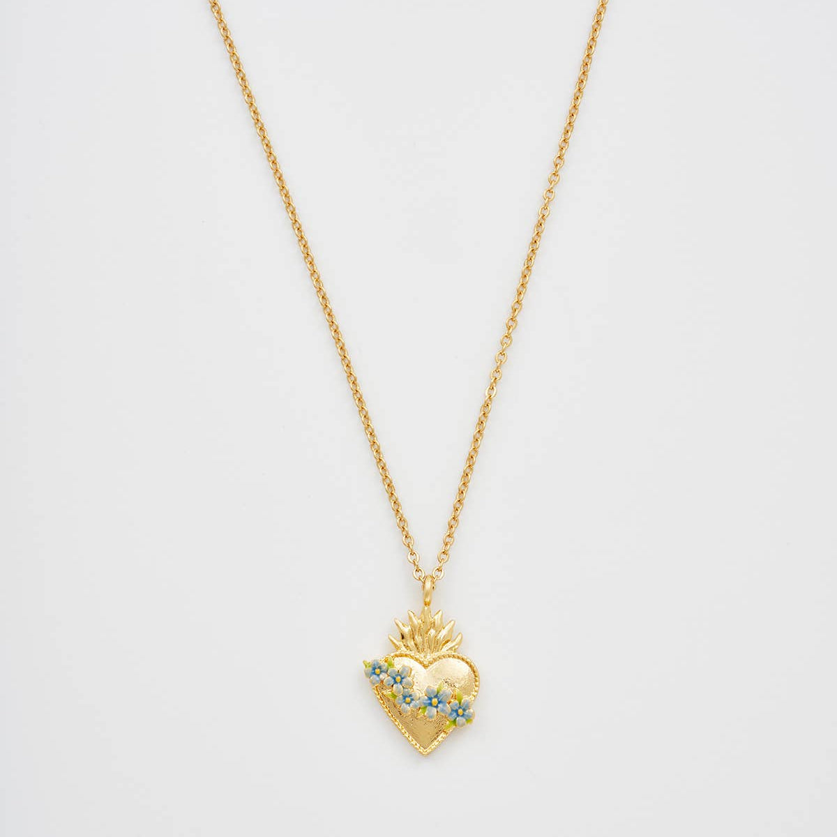 Close-up of gold sacred heart pendant with blue floral enamel.