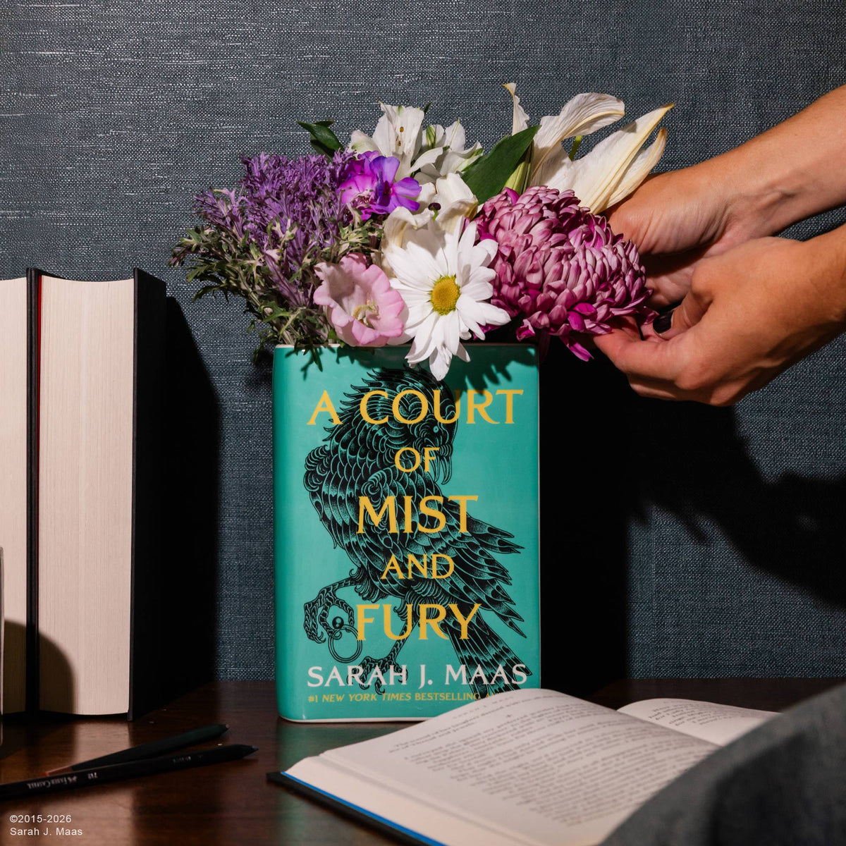 A Court of Mist and Fury Book Vase filled with mixed flowers on a desk