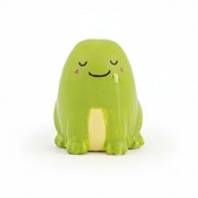 Green ceramic frog token with a sleepy smiling face, front view on white