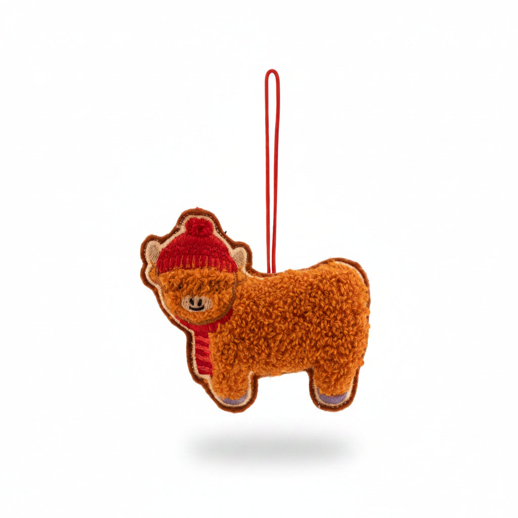 Fluffy boucle Highland cow decoration in a red bobble hat and scarf