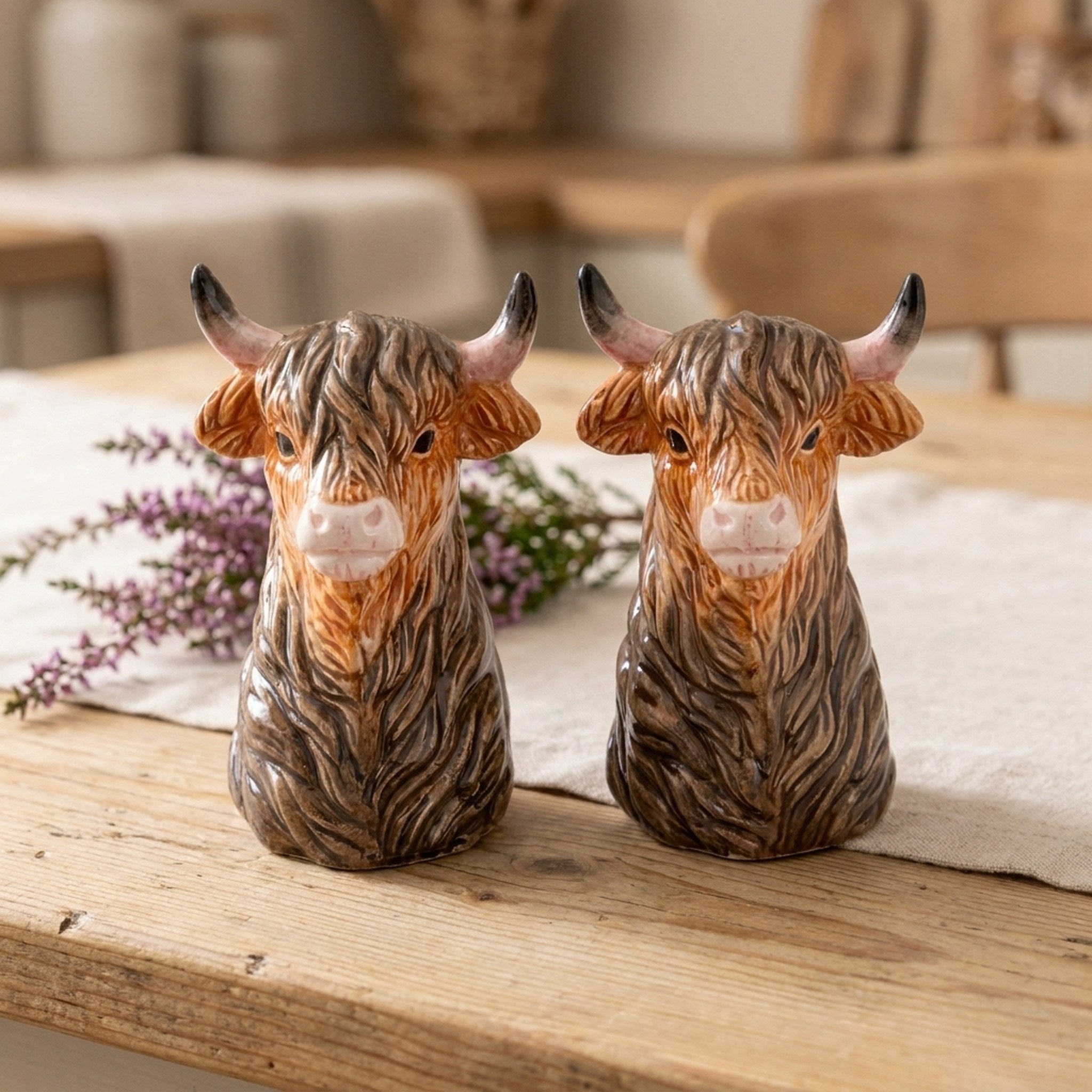 Highland Cow Head Salt and Pepper Shakers on a wooden table with heather