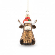 Glass Highland cow bauble in a red Santa hat with holly trim