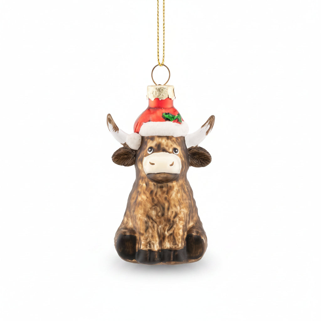 Glass Highland cow bauble in a red Santa hat with holly trim