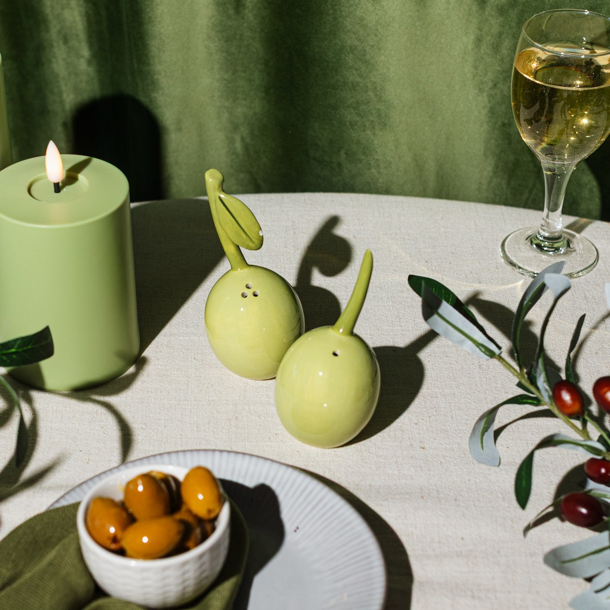Olive shakers styled on a dining table with olives and candlelight
