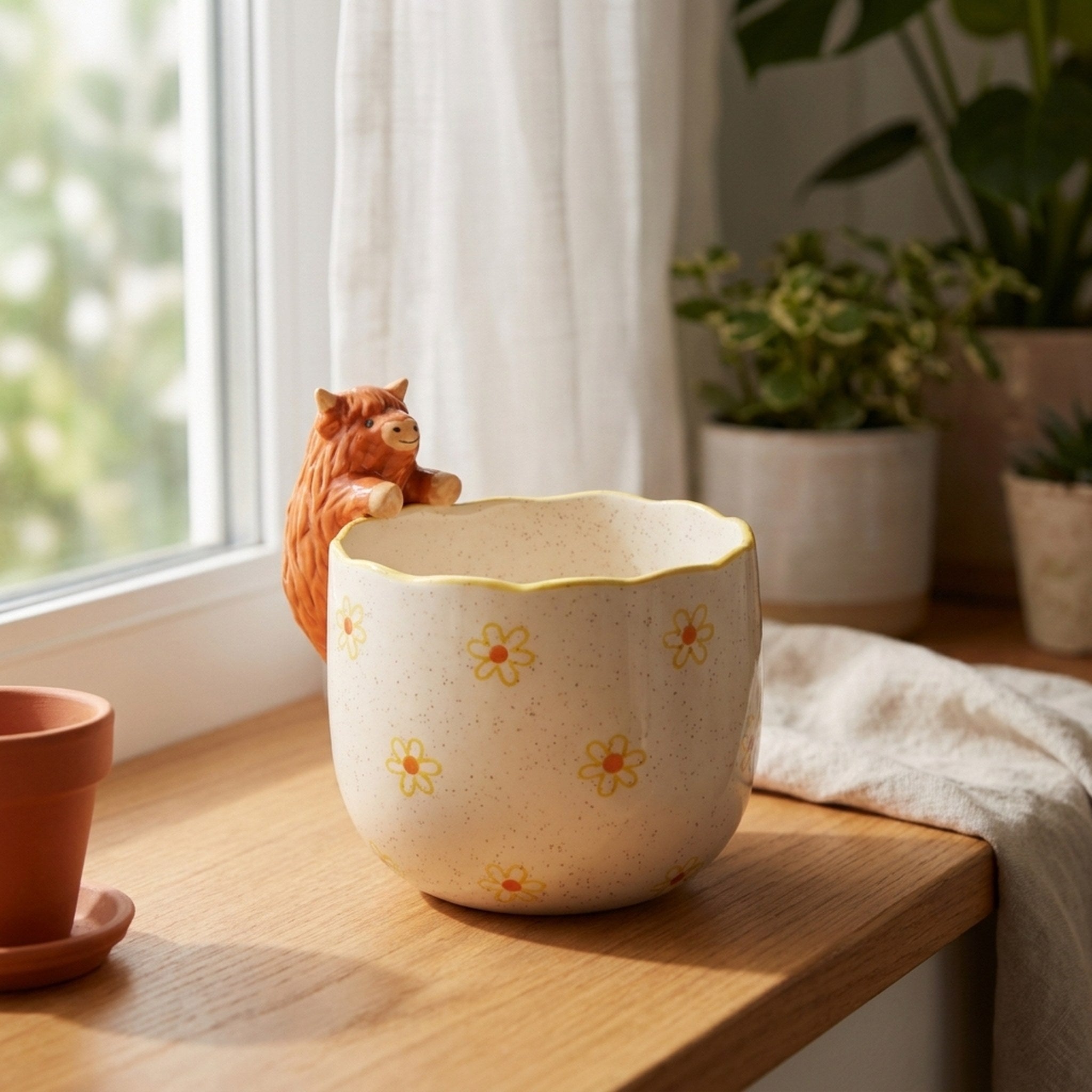 Peeking Highland Cow Planter on a bright windowsill beside a terracotta pot