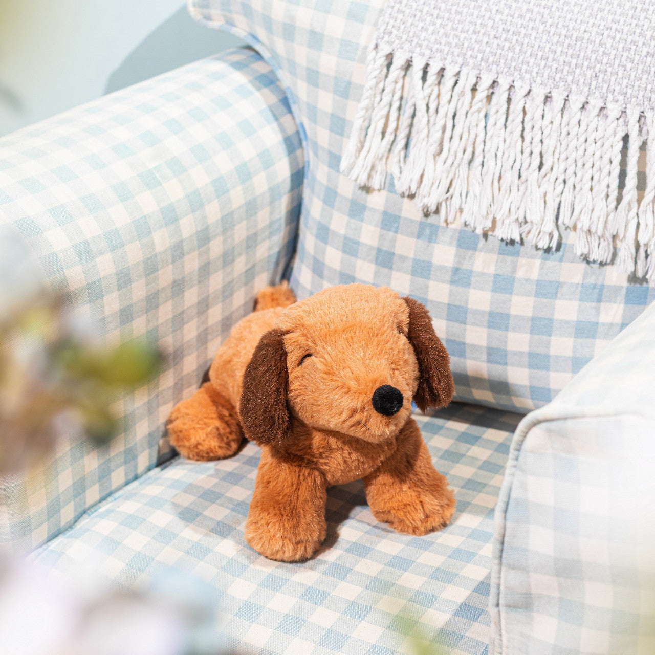 Sausage dog soft toy resting on a pale blue gingham armchair