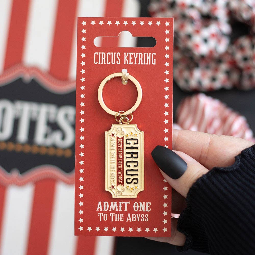 Keyring on red packaging card with striped cup on wooden surface