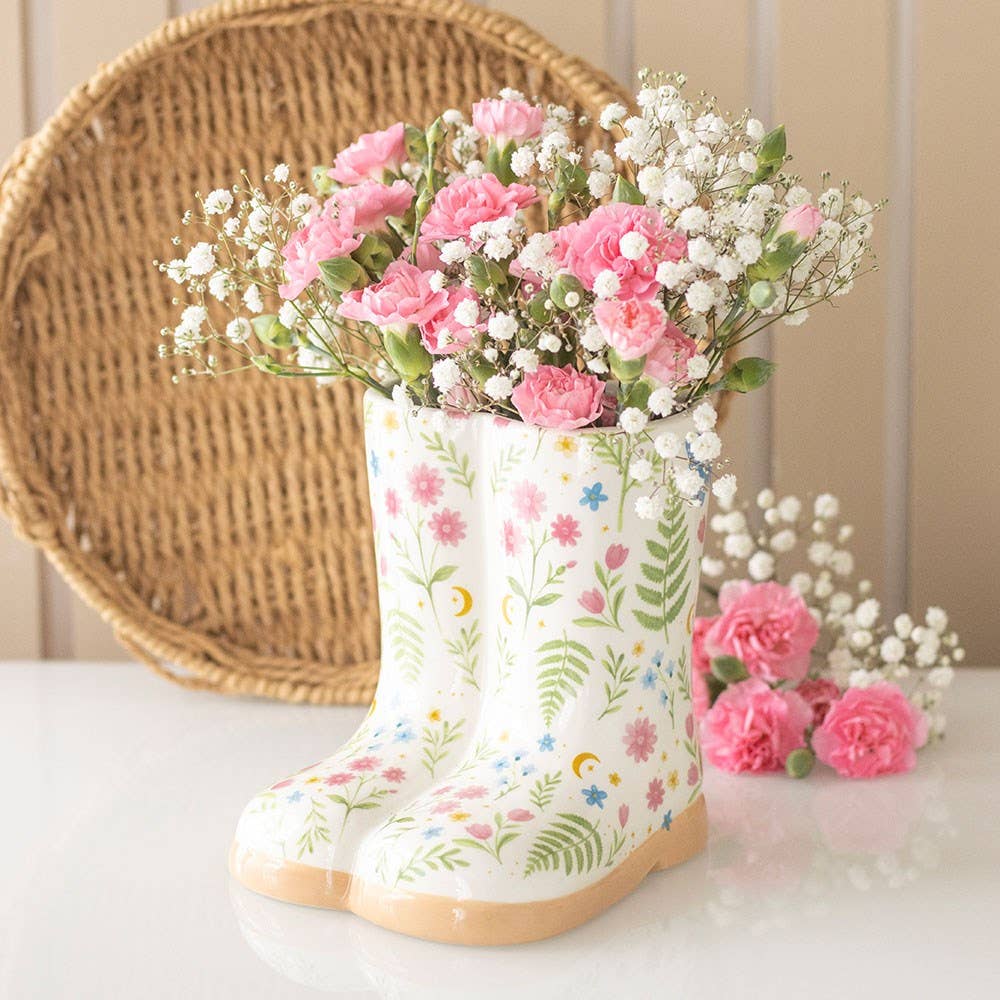 Welly boot planter with floral print and living plant on wooden surface