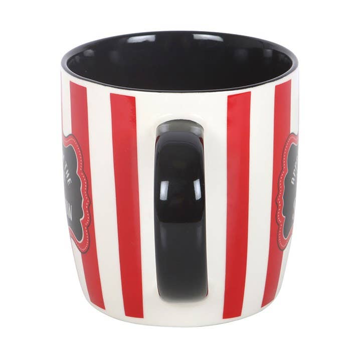 Lifestyle shot of mug near circus-themed items on dark surface