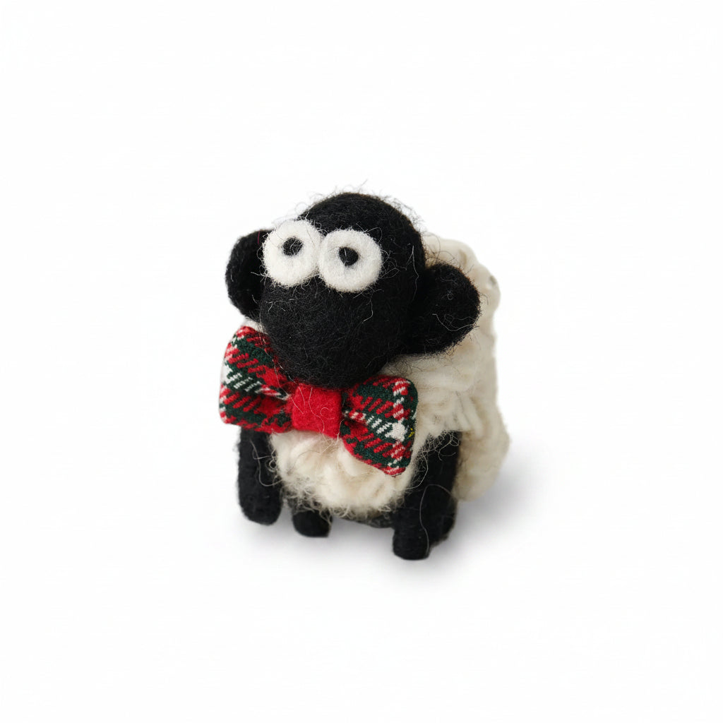 Knitted wool sheep keyring wearing a red tartan bowtie, on a plain grey background.