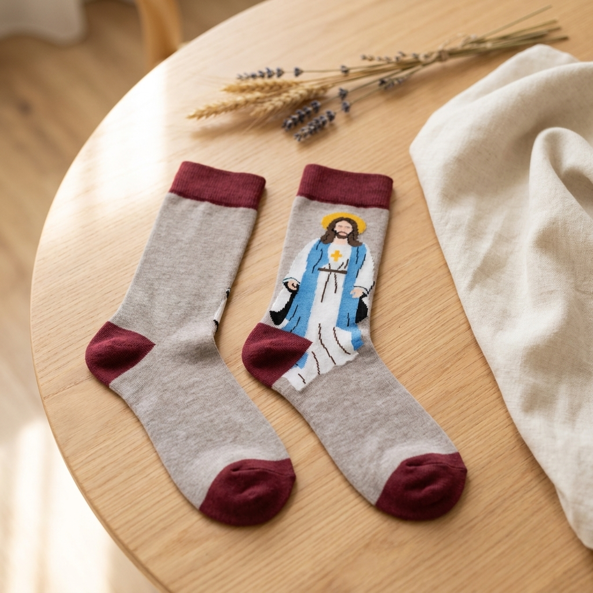 Jesus Sunday socks styled on warm light wood with cream linen and dried flowers