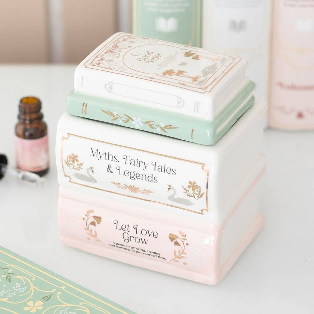 Ceramic book stack oil burner with essential oil bottle and candles in lifestyle shot