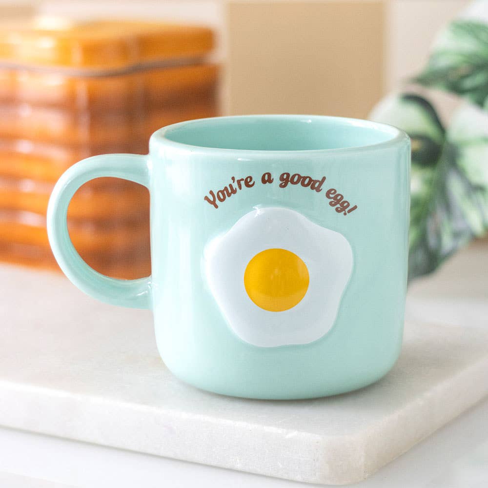 Mint green good egg mug styled on marble tile with toast rack and plant