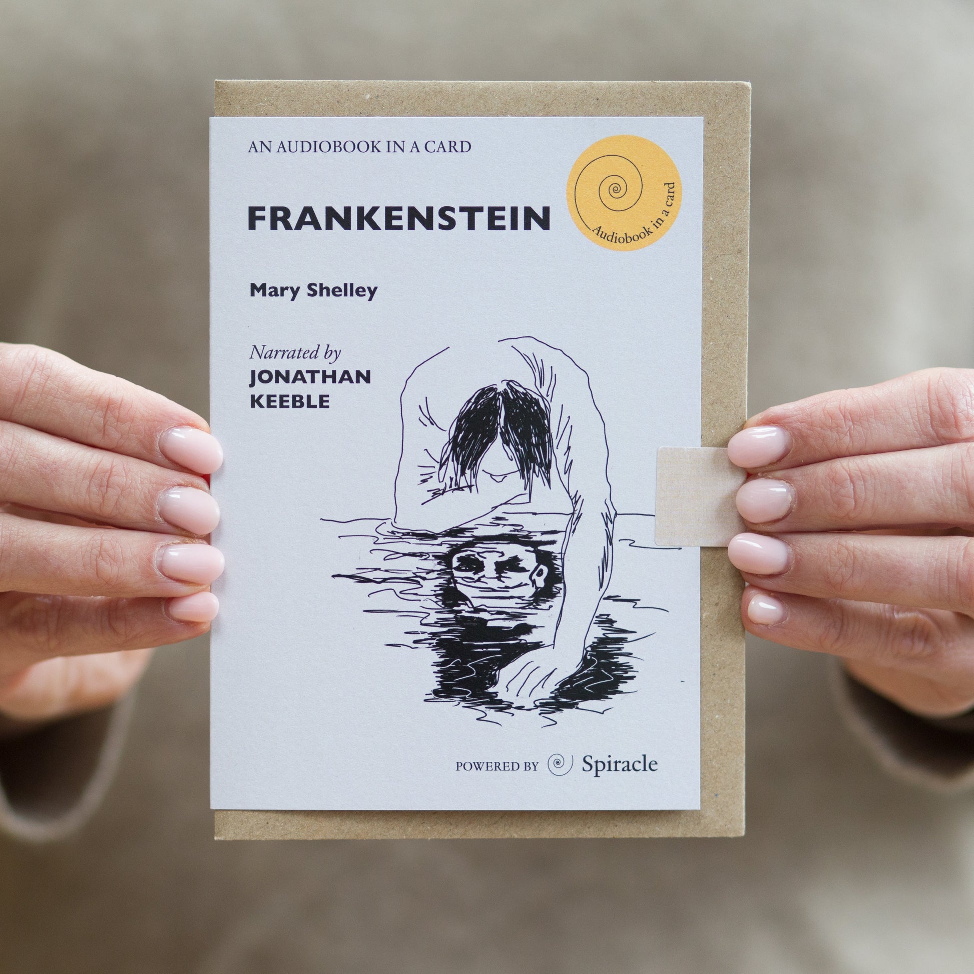 Hand holding the Frankenstein audiobook card to show its size