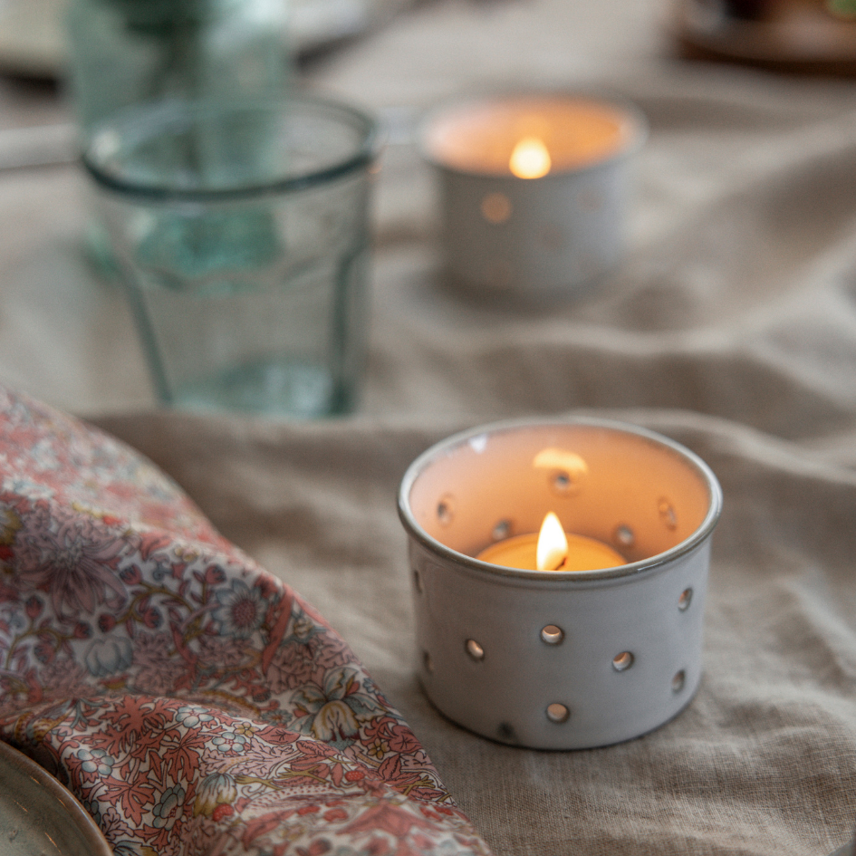 Glazed Ceramic Tealight Holder with a lit tealight glowing on a table