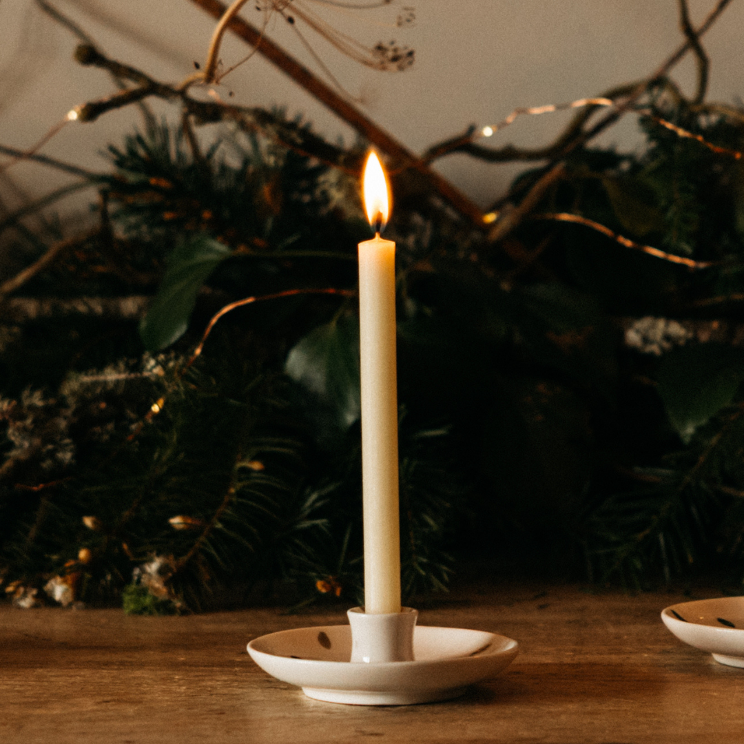 Inspiritus mini festive candle lit in a holder on a wooden table